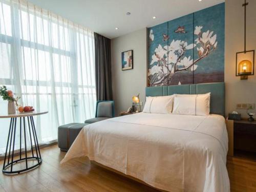 a bedroom with a large white bed and a chair at Magnotel Tongxiang Shimao Center in Tongxiang