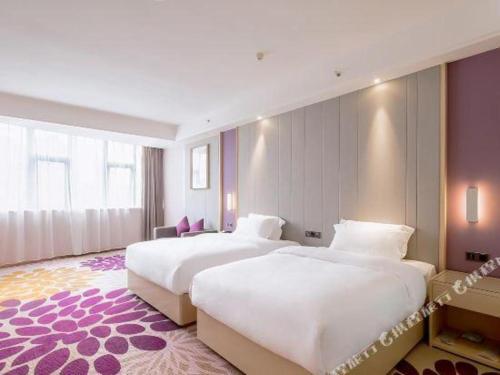 2 łóżka w pokoju hotelowym z fioletowymi ścianami w obiekcie Lavande Hotels· Yueyang Linxiang Zhongfa w mieście Linxiang