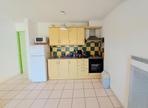a kitchen with yellow cabinets and a white refrigerator at soleil catalan latour bas elne 65m2 2ch ok animaux 4 pers chéques vacances in Latour-Bas-Elne