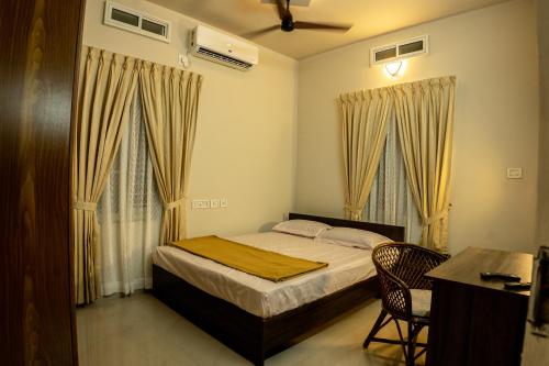 a bedroom with a bed and a desk and two windows at Siby Homestay in Ernakulam