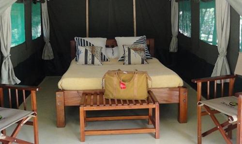 a bedroom with a bed with a yellow bag on it at Ol Moran Tented Camp in Ololaimutiek