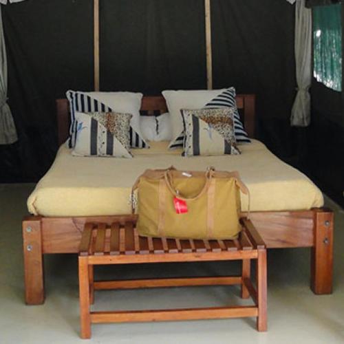 a bed with a bench with a bag on it at Ol Moran Tented Camp in Ololaimutiek