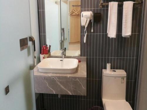 ein Badezimmer mit einem Waschbecken, einem WC und einem Spiegel in der Unterkunft Thank Inn Hotel Sichuan Nanchong Gaoping District Longmen 