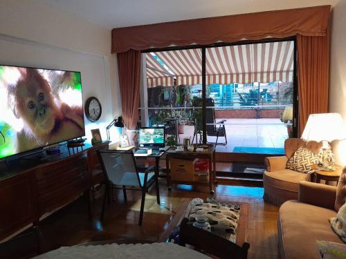 uma sala de estar com uma televisão de ecrã grande e um sofá em Terraza Santa Lucia,Suites "Como en su Casa" em Santiago