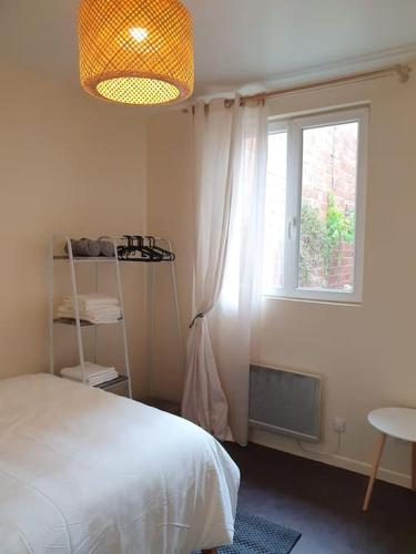 une chambre avec un lit blanc et une fenêtre dans l'établissement 2-room apartment with terrace near Paris, à Épinay-sur-Seine