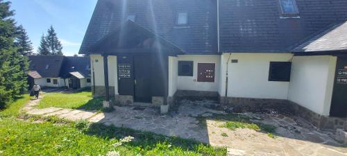 a house with a black roof and a person walking past it at Apartma Rogla Gaber 110 in Zreče