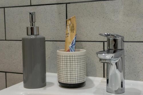 a bottle of mouthwash and a cup on a sink at CraftFlat Kalamaja A in Tallinn