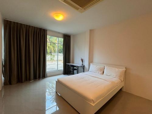 a bedroom with a bed and a window with a desk at San Peak Villa in Sam Roi Yot