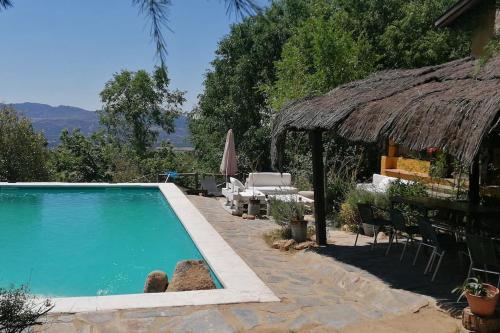 ein Pool neben einem Haus mit Strohdach in der Unterkunft villa pedriza I in Mataelpino
