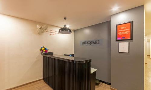 a lobby with a black counter and a sign on the wall at Treebo Trend The Square in Ahmedabad