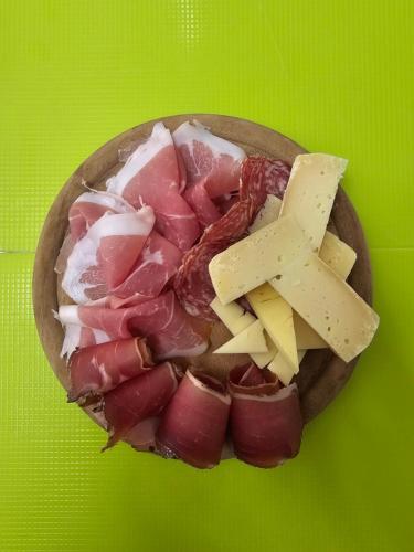 a plate of meat and cheese on a green table at Hotel Ideal in Sarche di Calavino