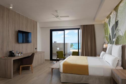 a hotel room with a large bed and a desk at Serenade All Suites - Adults Only Resort in Punta Cana