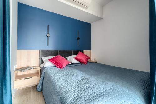 a bedroom with blue walls and a bed with red pillows at Apartamenty Solaris in Darłówko