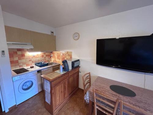 a small kitchen with a table and a tv on the wall at Studio climatisé avec jardin et plage à 250m in Saint-Mandrier-sur-Mer