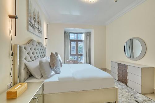 a white bedroom with a large bed and a mirror at Burj khalifa view 1BR Souk al Bahar Tajer Residences Mint avenue Downtown Golden Homes in Dubai