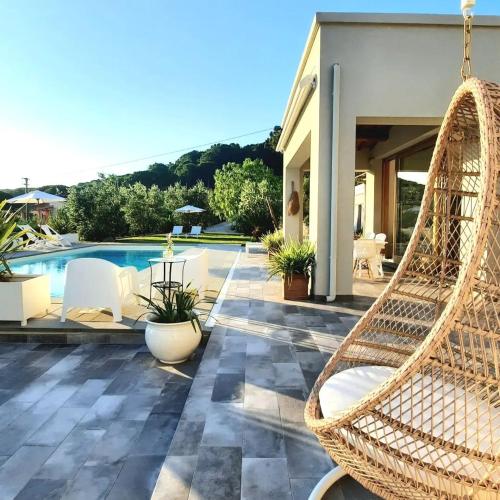 ポルトフェッラーイオにあるLa Suite con Piscina Privataのプール付きのパティオにある揺れる籐の椅子