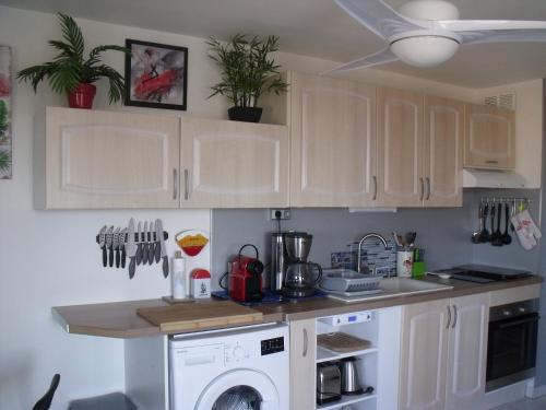 une cuisine avec des armoires blanches et une machine à laver dans l'établissement Appartement T2, 7 JOURS MINIMUM, Climatisé, 3 étoiles, 40m2 ,parking privé, Mer 300m, Wifi, Piscines, très propre, Ascenseurs, en étage, au Grau-du-Roi