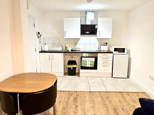 a kitchen with white cabinets and a wooden table at Great Value Bath Street Ilkeston Apartment in Ilkeston