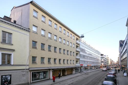 un edificio en una calle de la ciudad con coches aparcados en Kotimaailma Apartments Kamppi - 1BR for 3 persons, en Helsinki