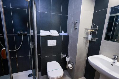 a bathroom with a shower and a toilet and a sink at Hotel SOREA REGIA in Bratislava