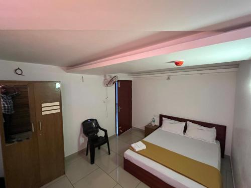 a bedroom with a bed and a chair and a door at Plaza Residency in Badagara