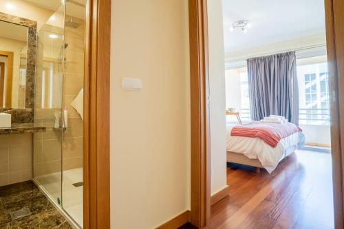 a bedroom with a bed and a glass shower at Green Park Ajuda Apartment in Funchal