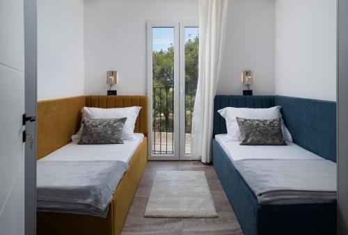 two beds in a room with a window at Luxury Villa Salt & Stone with spa area in Nin in Nin