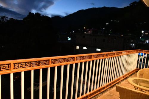 Una barandilla de madera en un balcón por la noche en Hotel The Crown, Dharamshala, en Dharamshala