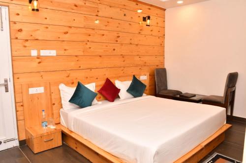 1 dormitorio con 1 cama con pared de madera en Hotel The Crown, Dharamshala, en Dharamshala
