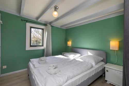 een slaapkamer met een groot wit bed en groene muren bij Chalet - Dorpsstraat 25 - Biggekerke 'De Weide Blick' in Biggekerke