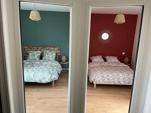 a reflection of a bedroom with two beds and a mirror at Maison charmante pour 4/6 pers in Brassac-les-Mines