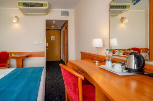 a hotel room with a desk with a bed and a mirror at Mercure Czestochowa Centrum in Częstochowa