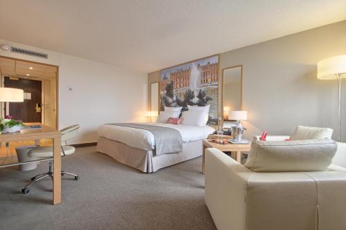 a hotel room with a large bed and a desk at Mercure Paris Velizy in Vélizy-Villacoublay