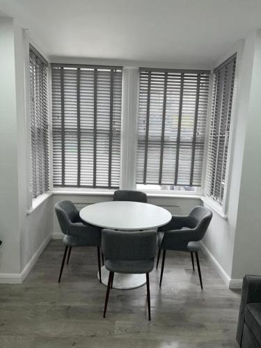 a table and chairs in a room with windows at Luxe Ground Floor Apt/Free Parking/Private Garden in Redbridge
