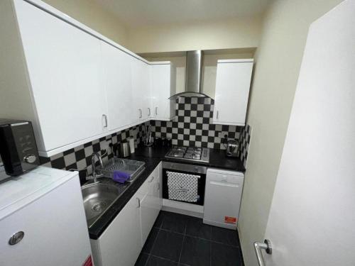 a small kitchen with a sink and a stove at Luxe Ground Floor Apt/Free Parking/Private Garden in Redbridge