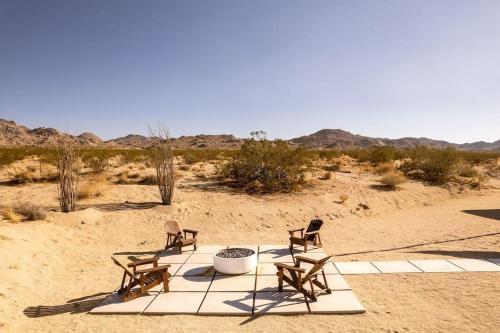three chairs sitting on a blanket in the desert at Joshua Tree Luxury Home With Hot Tub & views in Joshua Tree
