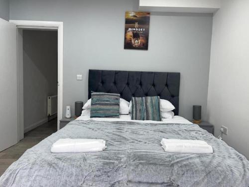 um quarto com uma cama grande e 2 almofadas em Luxe Ground Floor Apt/Free Parking/Private Garden em Redbridge