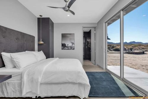 a bedroom with a white bed and a large window at Joshua Tree Luxury Home With Hot Tub & views in Joshua Tree