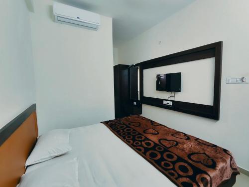 1 dormitorio con 1 cama y TV en la pared en Hotel Heritage Palace en Bhuj