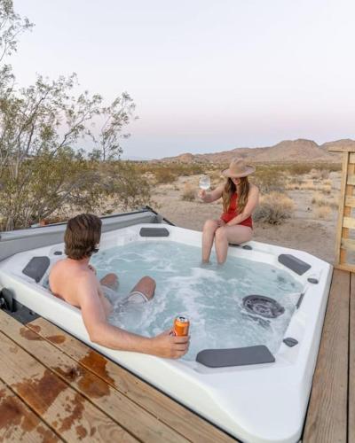 a man and a woman sitting in a hot tub at Joshua Tree Luxury Home With Hot Tub & views in Joshua Tree