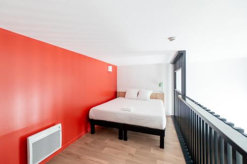 a bedroom with a bed and a red wall at ECLA Paris Massy Palaiseau in Palaiseau