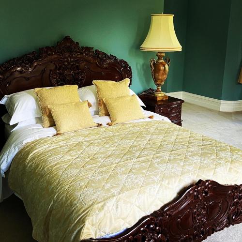 a large bed in a green bedroom with a lamp at Ashleigh Buxton in Buxton