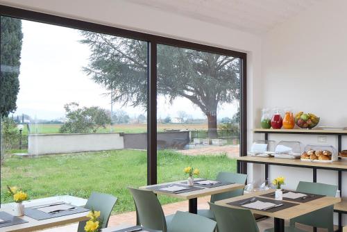 une salle à manger avec des tables et des chaises ainsi qu'une grande fenêtre dans l'établissement Luci di Assisi B&B Wellness, à Assise