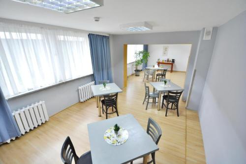 uma sala de jantar com mesas, cadeiras e janelas em Twój Hostel Bytom em Bytom