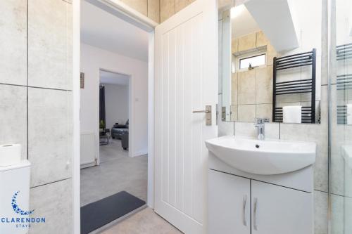 レミントン・スパにある3BR Home with Driveway Leamington Spa Town Centreの洗面台と鏡のある白いバスルーム
