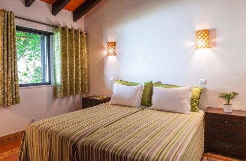 a bedroom with a bed with two pillows and a window at Pedras D'el Rei in Tavira