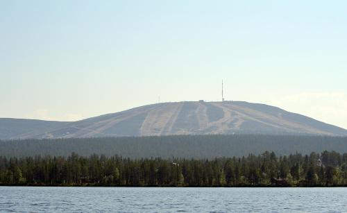 a mountain with trees in front of a body of water at Talo Ylläs in Äkäslompolo