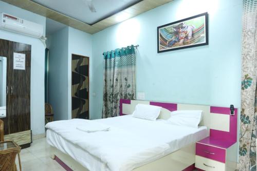 een slaapkamer met een wit bed en blauwe muren bij Radhe Radhe Guest House in Dehradun