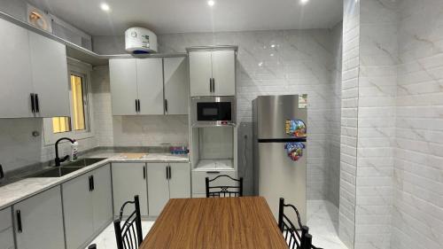 a kitchen with a wooden table and a refrigerator at شقة غرفتين وصاله in Al ‘Uqūl