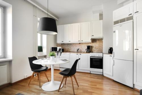 a kitchen with white cabinets and a white table and chairs at Kotimaailma Apartments Kamppi - spacious 1BR in Helsinki